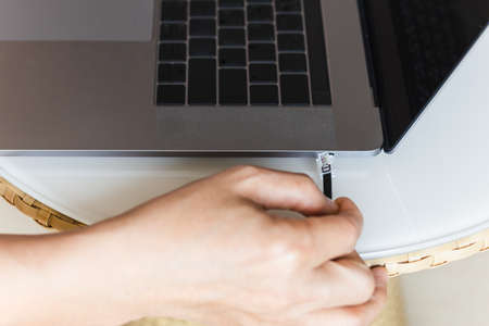Man hand holding internet cable wire with laptop in background.