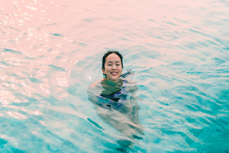 Beautiful woman smiling in a swimming pool under the summer light.の写真素材