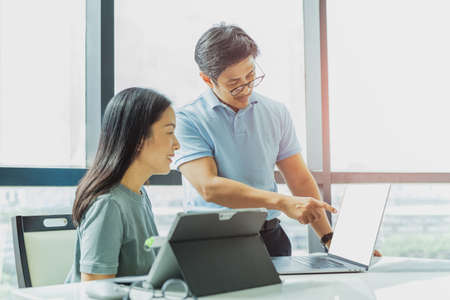 Businessman and woman working together with his hand pointing on laptop.