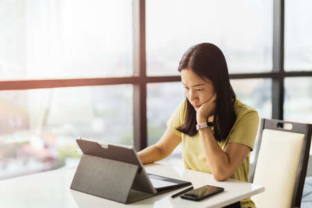Thoughtful woman working on tablet computer at home.