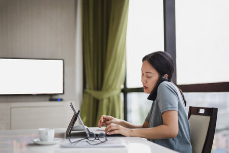 Woman holding smart phone with shoulder and typing on the laptop keyboard,の写真素材