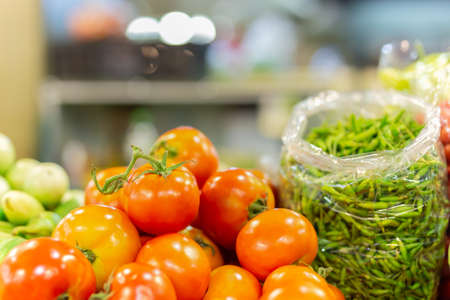Fresh organic tomato pile and green chilli in harvest store.の写真素材