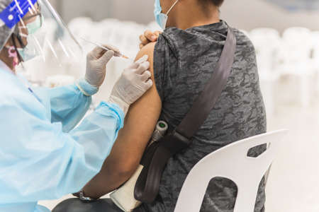 Doctor injecting vaccine to male patient against  virus pandemic.の写真素材