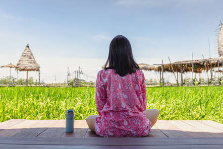 Woman sitting on wooden floor with thermos bottle look at beautiful landscape.の写真素材
