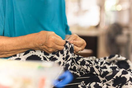 Elderly woman hands using needle and thread to mend a dress.の写真素材
