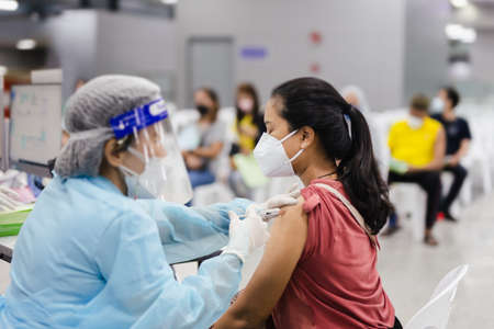 Doctor in protective suit giving patient a vaccineの写真素材