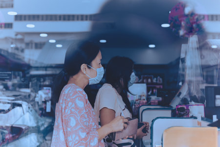 Woman in protective mask paying bill at cashier counter in market shop.の写真素材