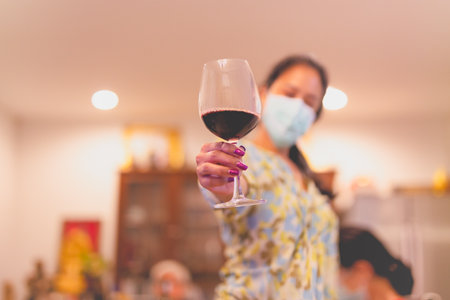 Women in protective mask holding red wine glasses celebration concept.の写真素材