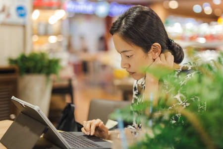 Concentrated beautiful woman using laptop computer in cafe.の写真素材