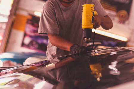 Car specialist tinting film for car glass with hairdryer.の写真素材