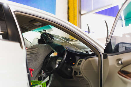 Male specialist applying window tinting film on the car.