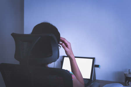 Stressed businesswoman hand on her head working on laptop late at night.