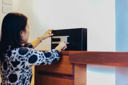 Woman opening black steel safe with electronic lock in hotel room.の写真素材