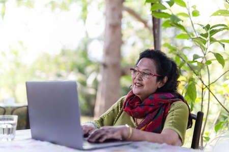 Senior woman wearing eyeglasses working on laptop.の写真素材