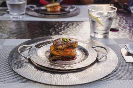Foie gras on silver plate with sauce.