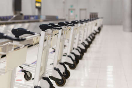 Empty airport luggage carts parking behind warning line in baggage claim area in terminal.の写真素材