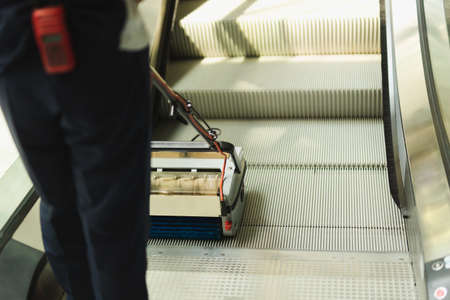 Male cleaner cleaning escalator with mechine in modern building.の写真素材