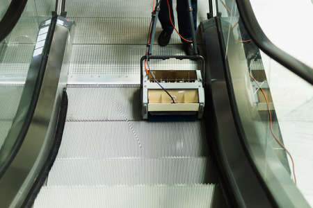 Male cleaner cleaning escalator with mechine in modern building.の写真素材