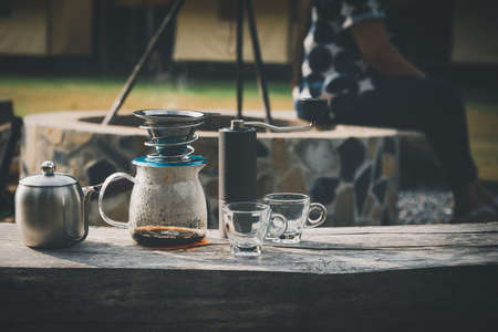 Coffee maker is placed on top of wooden chair in camping area.の写真素材