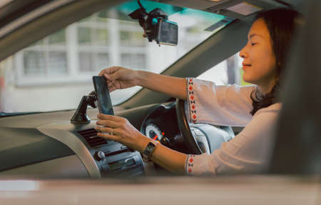 Woman driver hand adjust cell phone in stand holder for direction.の写真素材