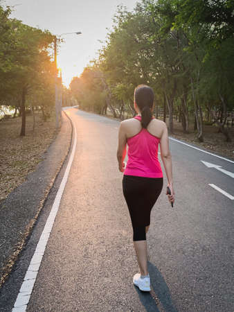 Full length woman exercise walking in the park with sunset.の写真素材