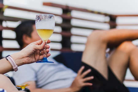 Woman holding a glass of beer on the beach.
