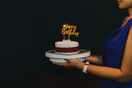 Woman holding birthday cake with candle and birthday plate.の写真素材