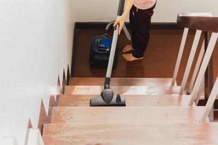 Asian young housekeeper hoovering stairwell in a house.の写真素材