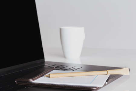 Mock up blank screen laptop and cup of coffee with other office supplies.