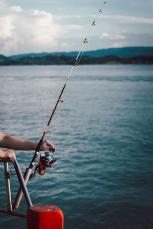 Fishing rod wheel closeup, man fishing from the boat in the sea.の写真素材