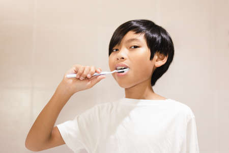 Boy brushing his teeth with toothbrush in the bathroom