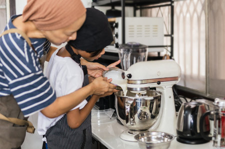 Young boy pouring egg yolk into electric mixer bowlの写真素材