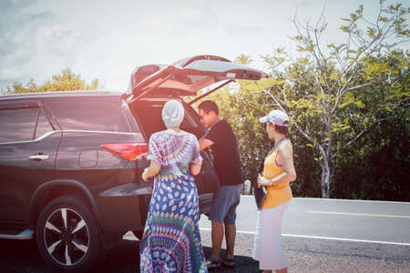 Man with female friends loading luggage in trunk of automobile on summer vacation tripの写真素材