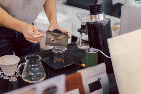 Barista meauring roasted coffee grains on a scale before brewing coffee.の写真素材