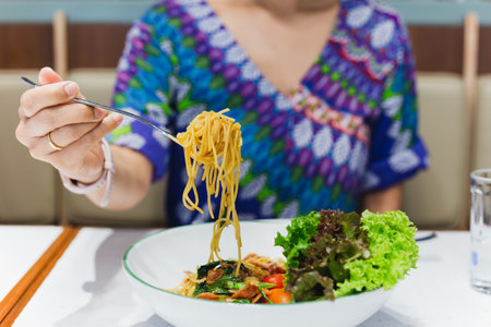 Hand holding fork eating spaghetti in restaurant.の写真素材