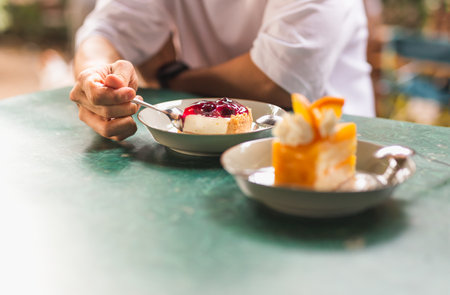 Man hand holding a spoon eating cheesecake in cafe.