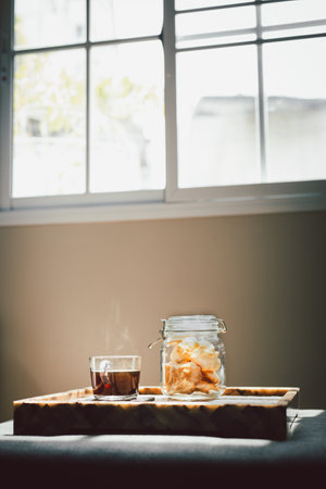 Glass of black coffee with jar of cookies in living room.