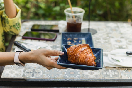 woman hand holding croissants on table in cafe outdoor.の写真素材