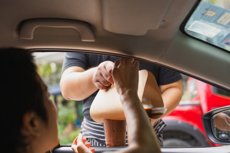 Waiter delivery iced coffee drink to customer in the car.の写真素材
