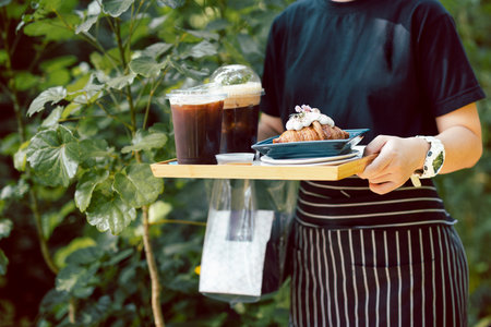 Waitress serving iced coffee and croissants in cafe outdoor.の写真素材