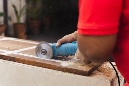 Hands of carpenter cutting piece of wood with electric circular saw.の写真素材
