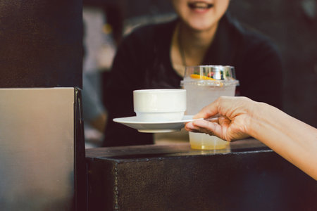 Woman barista serving cup of coffee at cafe.の写真素材