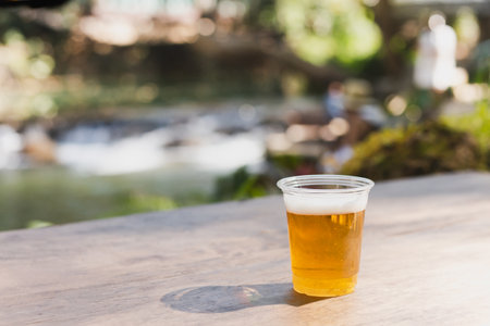 Isolated of beer in plastic glasse on wooden table.の写真素材
