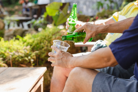 Man pouring beer in plastic glass from bottle during vacation.の写真素材