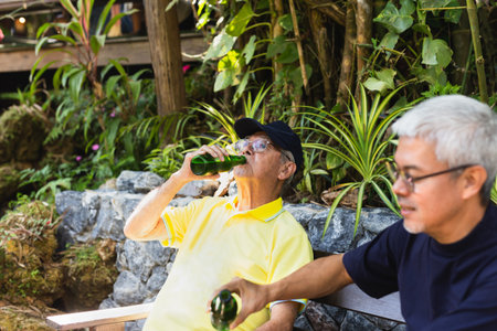Father and son sitting in chairs and drinking beer on vacation.