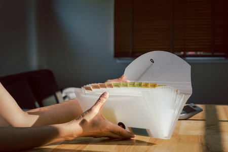 Woman hands organizing folder on a desk at home.の写真素材