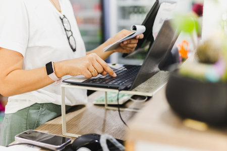 Woman restaurant owner working on laptop at cashier counter.の写真素材