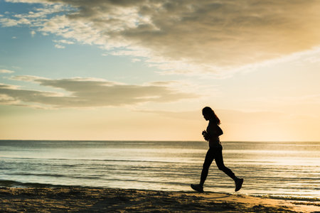 silhouette of three woman jogging on the beach at sunrise.の写真素材