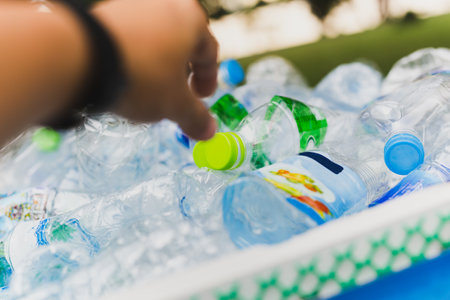 Hand put plastic bottles in to recycle garbage.