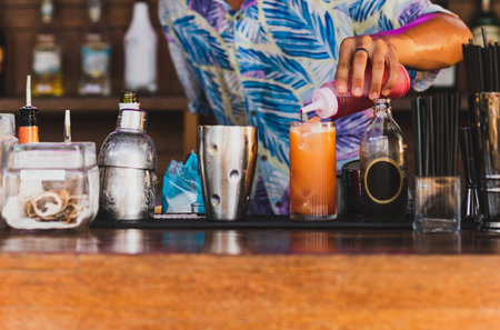 Bartender making cocktail topping with grenadine syrup at the bar